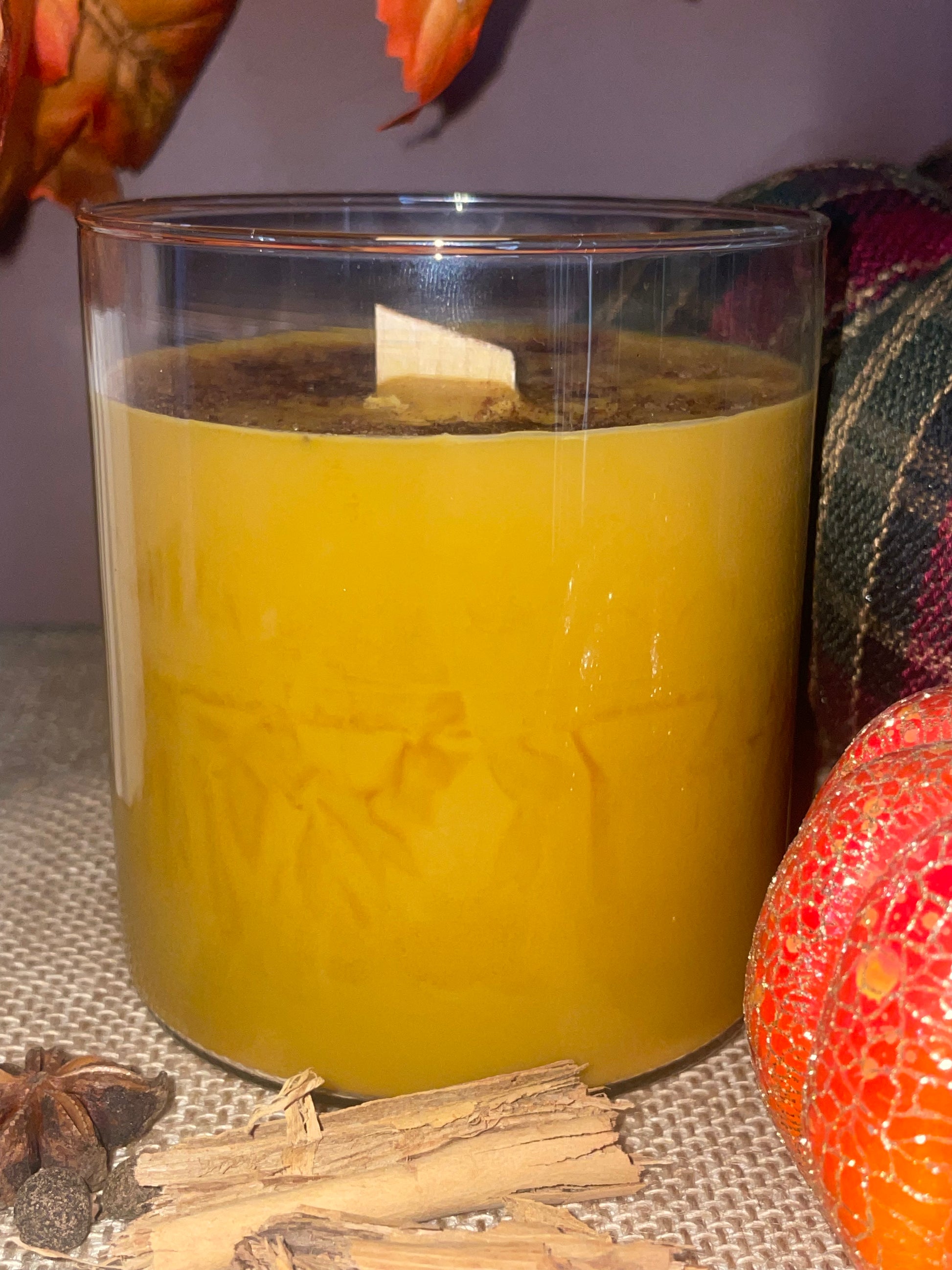 Golden candle in a glass container with decorative elements on a textured surface