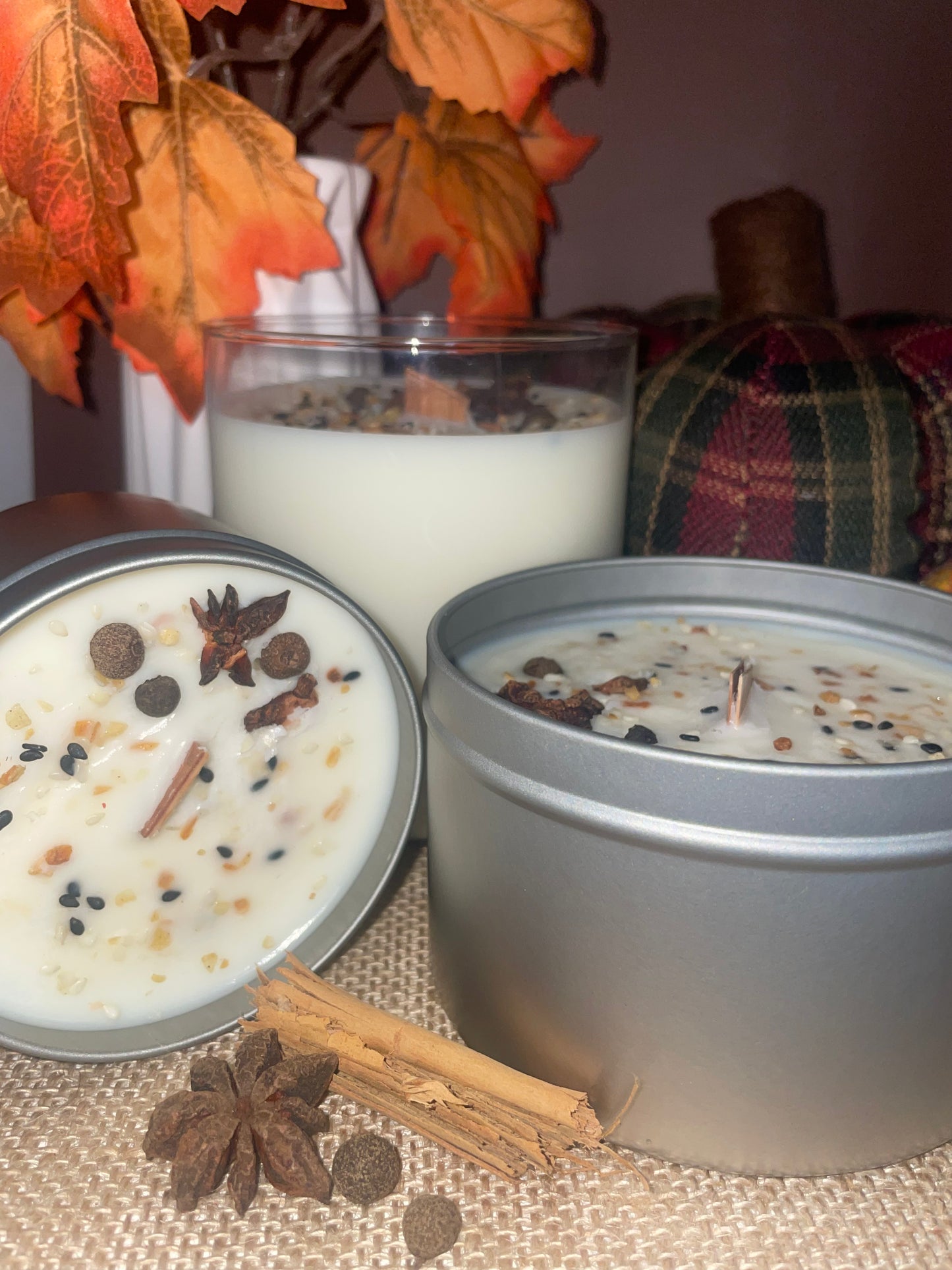 Three candles with visible spices and leaves on a textured surface